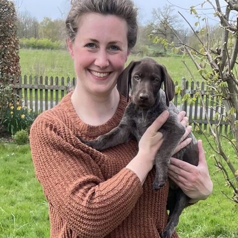 Fr. Dr. Lara Steinhoff mit Hund sitzendauf einer Wiese